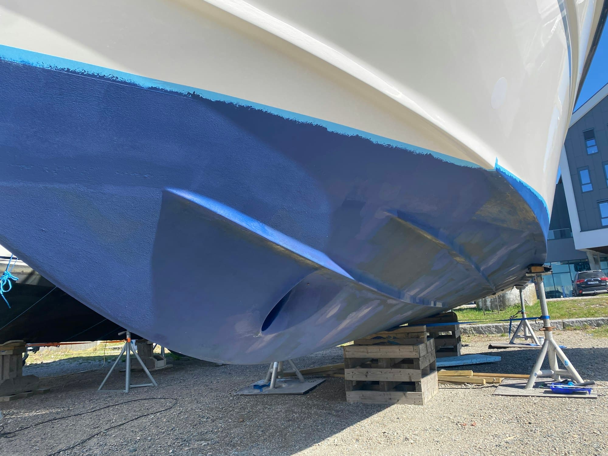 A yacht up on stands in a boatyard, fresh blue antifouling